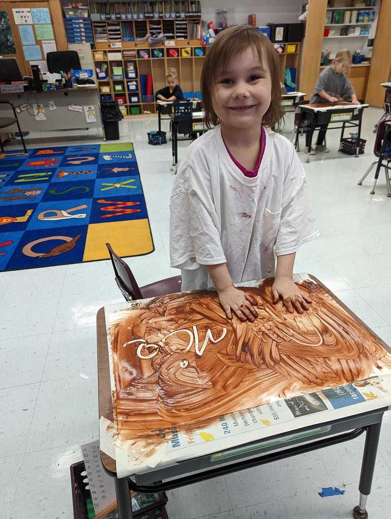 Kindergartener finger painting with pudding